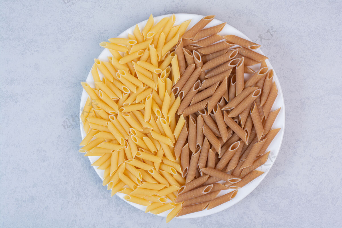 意大利面在白色盘子里放一堆棕色和黄色的意大利面吃盘子干的