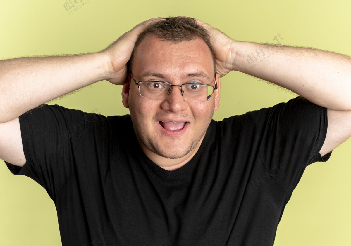男人一个戴眼镜的胖男人穿着黑色t恤看着摄像机疯狂地把头举过光墙超重光站