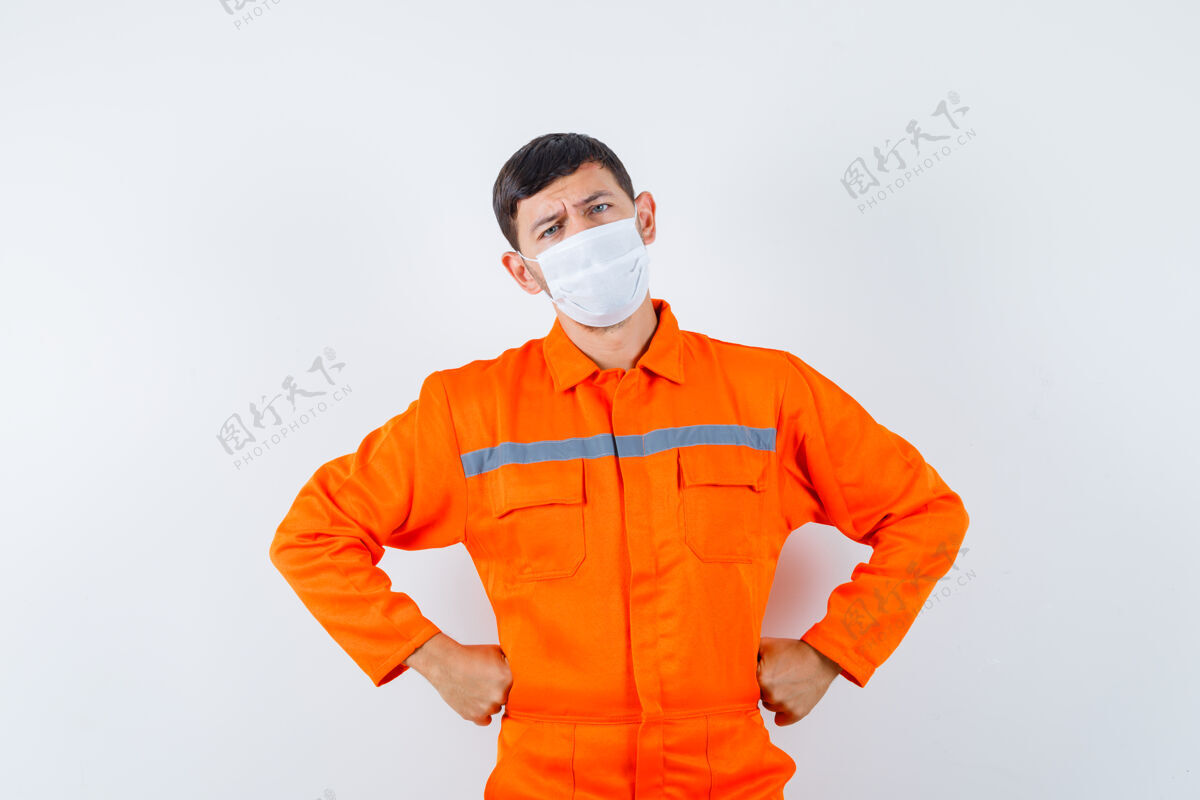 制造一个穿着制服 手放在腰上 戴着面具 神情沉思的工业工人前视图自动化操作工人