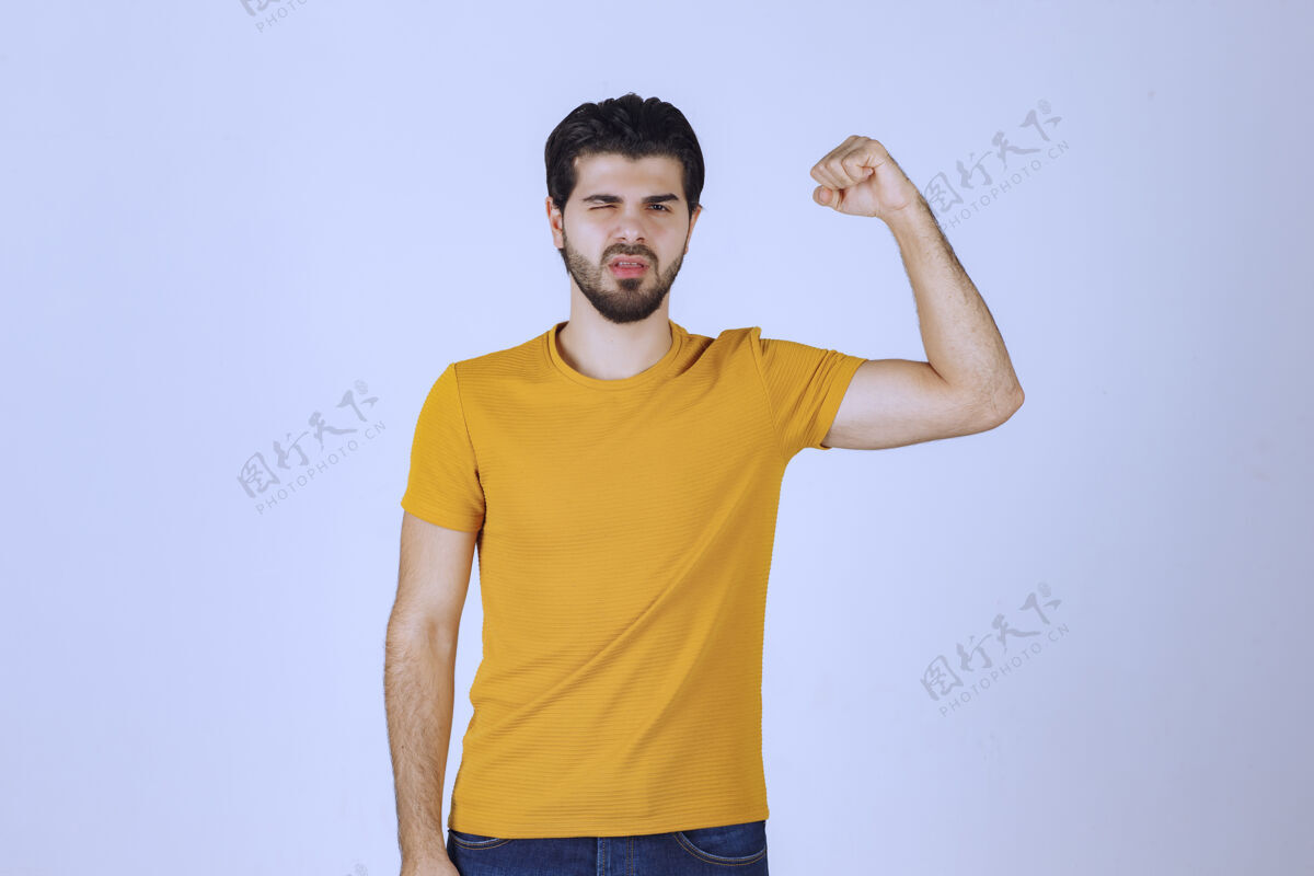 成人男人展示他的手臂肌肉和感觉强大姿势年轻交易