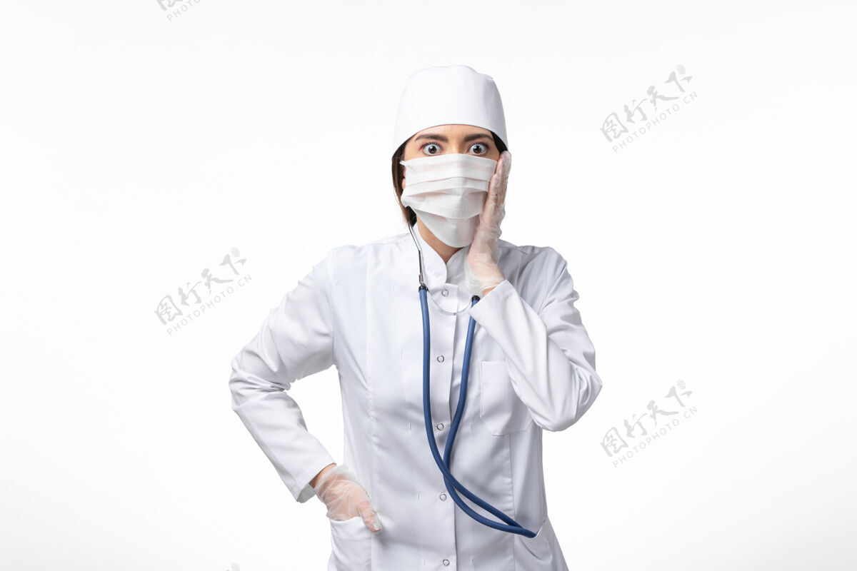 医生正面图女医生身穿白色无菌医疗服 带口罩 因冠状病毒在白墙病上有震惊的表达 大流行病毒covid-医学女性冠状病毒防护