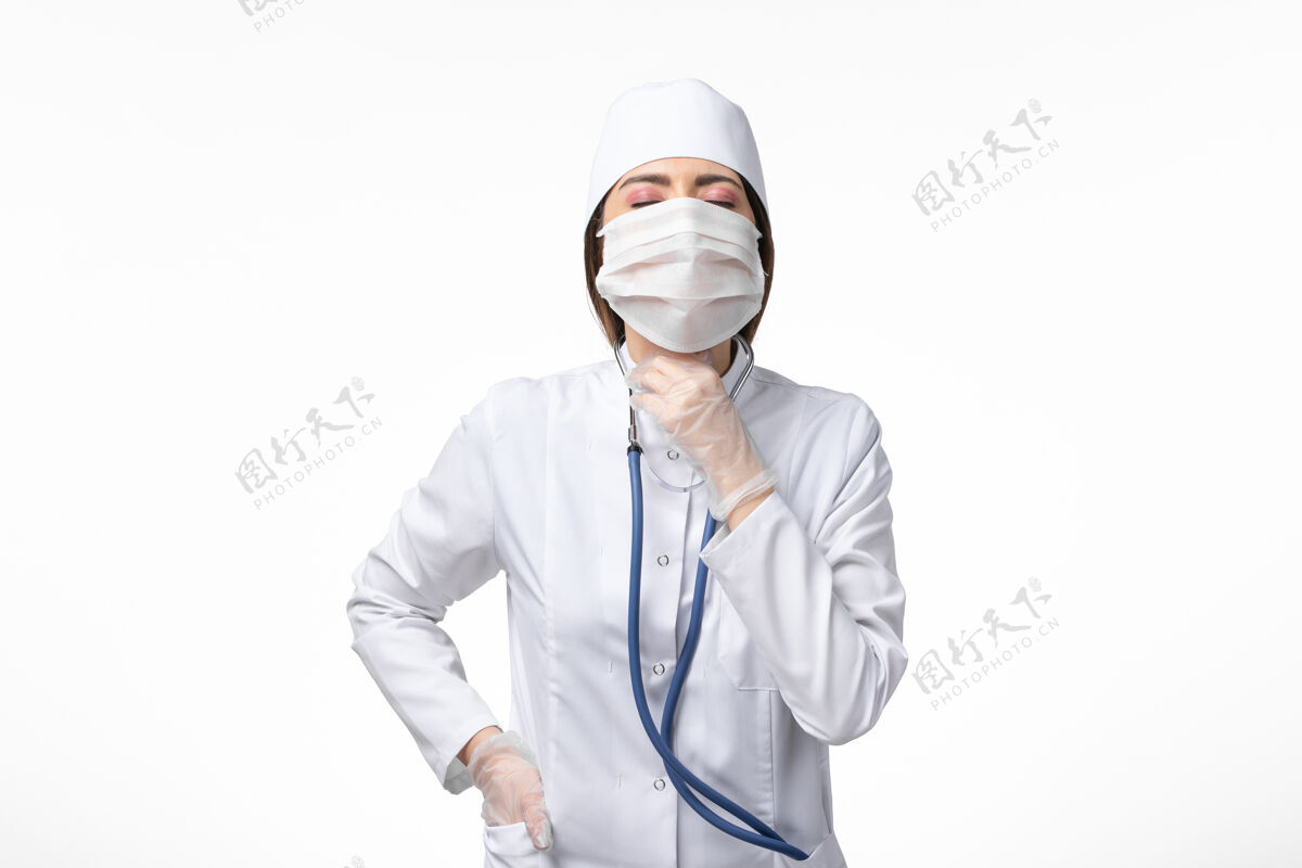 病毒正面图女医生穿着白色无菌医疗服 带口罩 因白墙上有冠状病毒病病毒冠状病毒疾病实验室外套冠状病毒防护