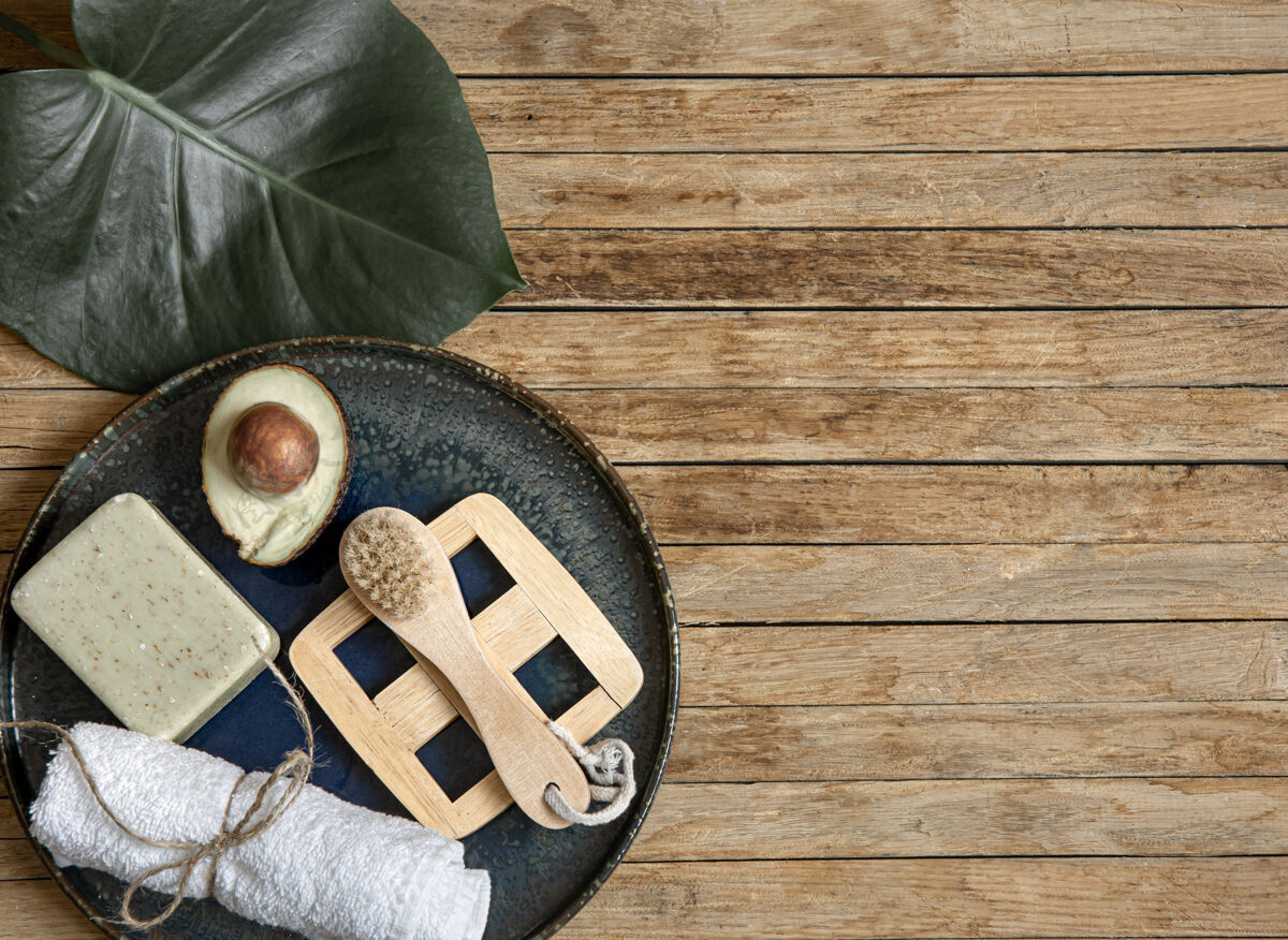 木材水疗用肥皂 鳄梨毛巾 刷子和叶子组成的木质表面复制空间手工叶子皮肤护理
