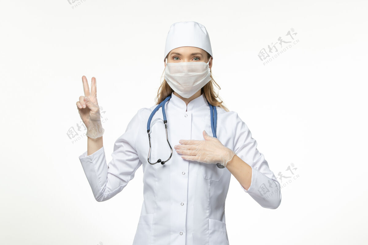 大流行前视图：穿着白色医疗服 戴着白色口罩的女医生在白色墙壁上疾病传播医务人员外套面罩