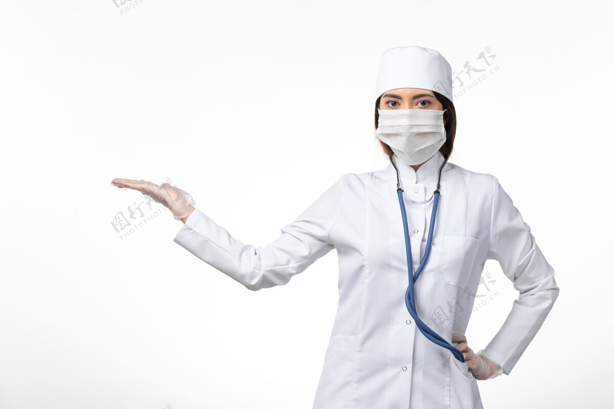 视图正面图女医生穿着白色医疗服 戴着口罩 因大流行在白色办公桌上 医药大流行病毒covid-人员药品正面