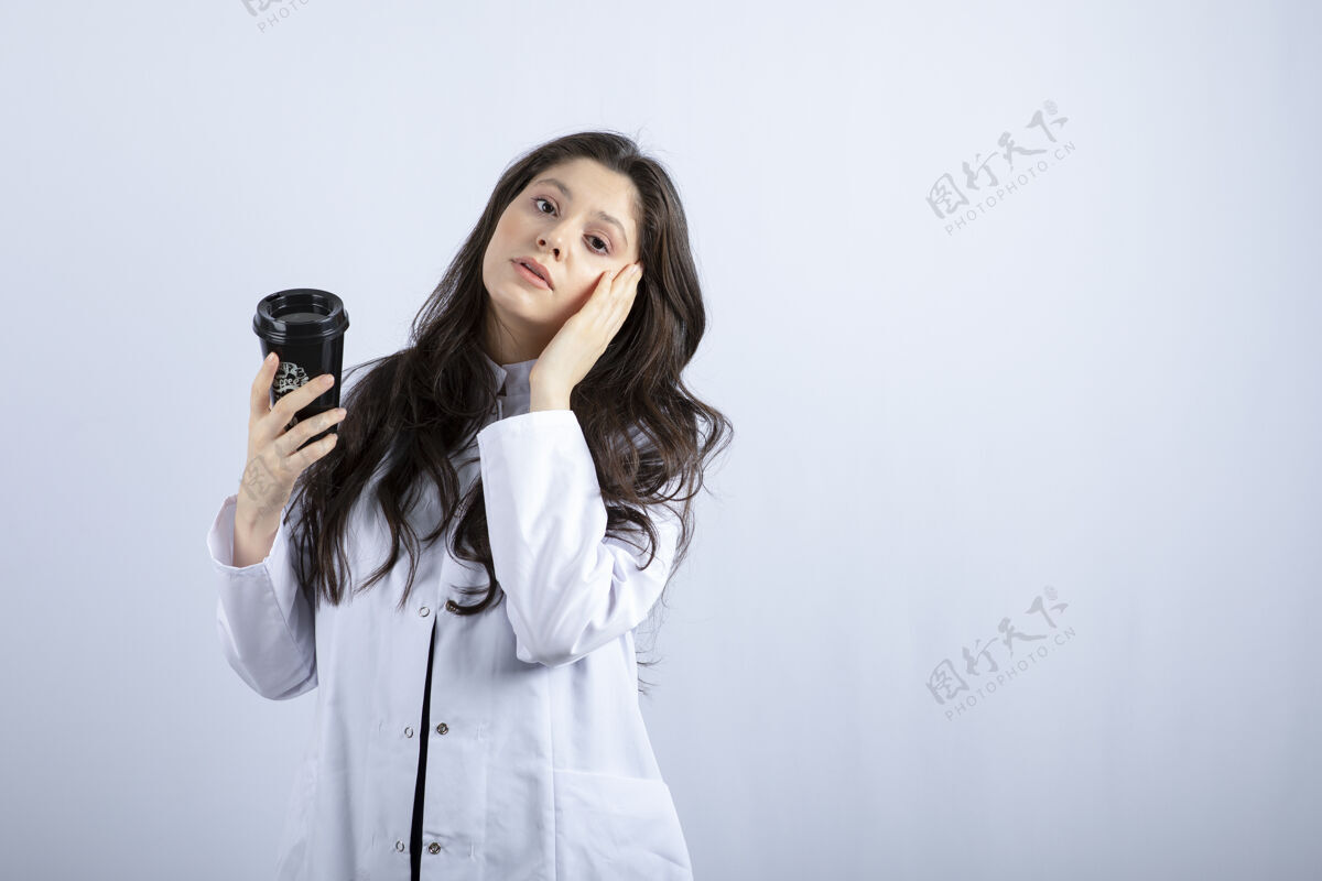 医生一张女医生的画像 她拿着一杯咖啡站在灰色的地板上保健冠状病毒工作