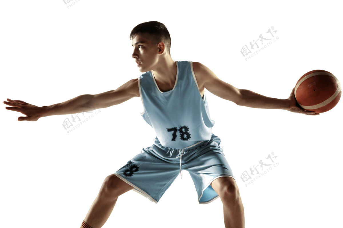 比赛一个年轻的篮球运动员与一个球在空白处孤立的全长肖像动作小伙子玩