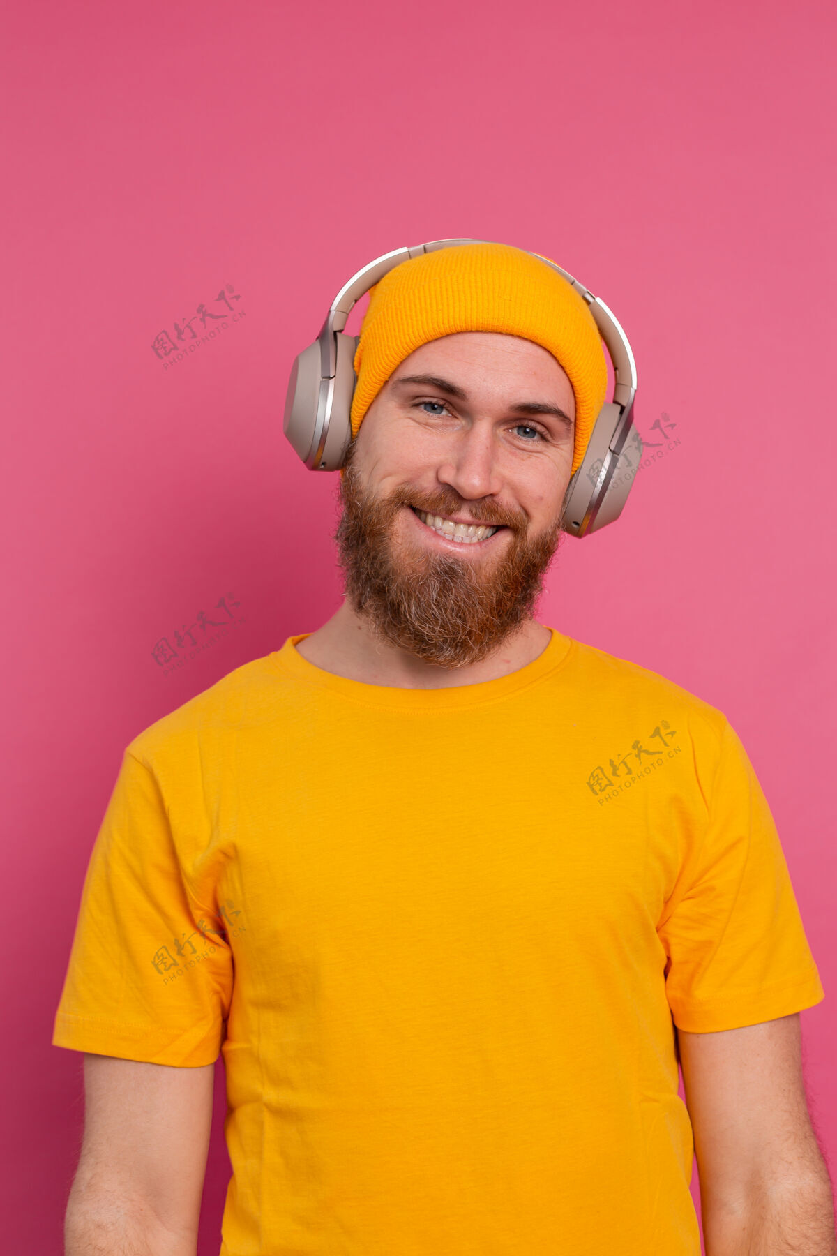 情人帅哥在随意地听着音乐 用耳机隔离在粉色背景上旋律模型背景
