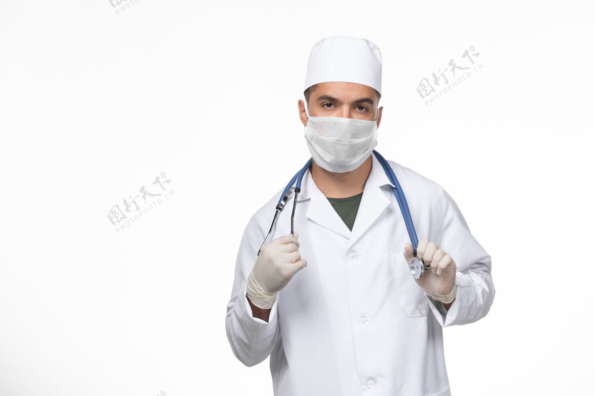外套正面图：男医生穿着医疗服 戴着防冠状病毒口罩 在白墙上进行冠状病毒-疾病隔离大流行听诊器正面疾病