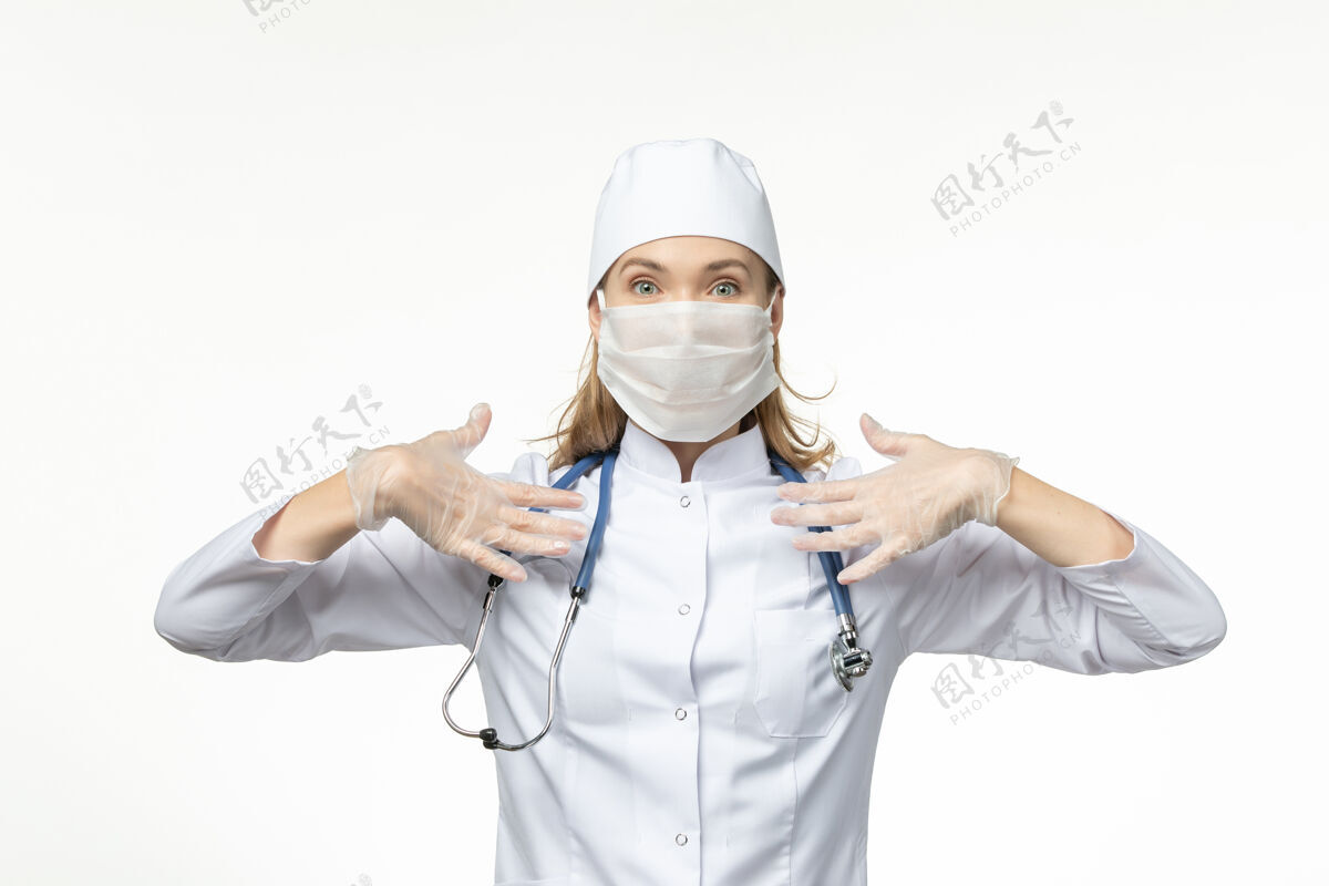 肖像正面图：女医生穿着白色医疗服 戴着防护面罩 因冠状病毒在淡白色的墙壁上传播疾病-大流行性疾病成人医学疾病