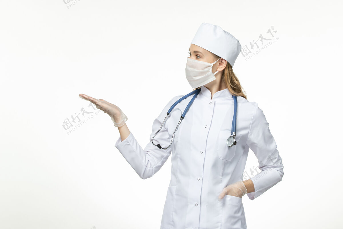 制服正面图女医生身穿医疗服戴口罩因冠状病毒对淡白色壁病冠状病毒-大流行性病毒病到期套装佩戴