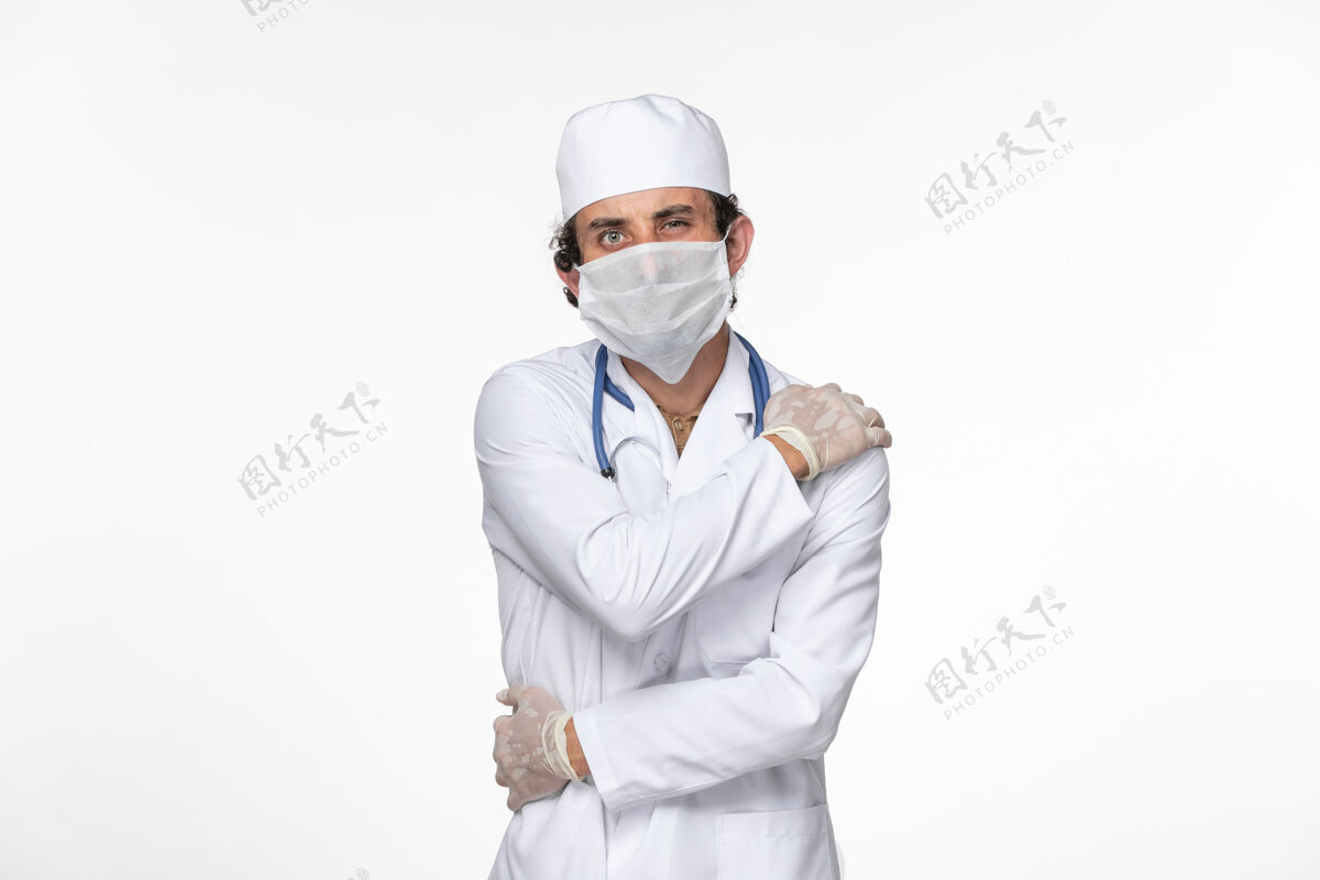 前面正面图男医生穿着医用西服 戴着无菌口罩作为防护罩 免受冠状病毒在白墙上溅起的冠状病毒大流行的危害消毒防护冠状病毒