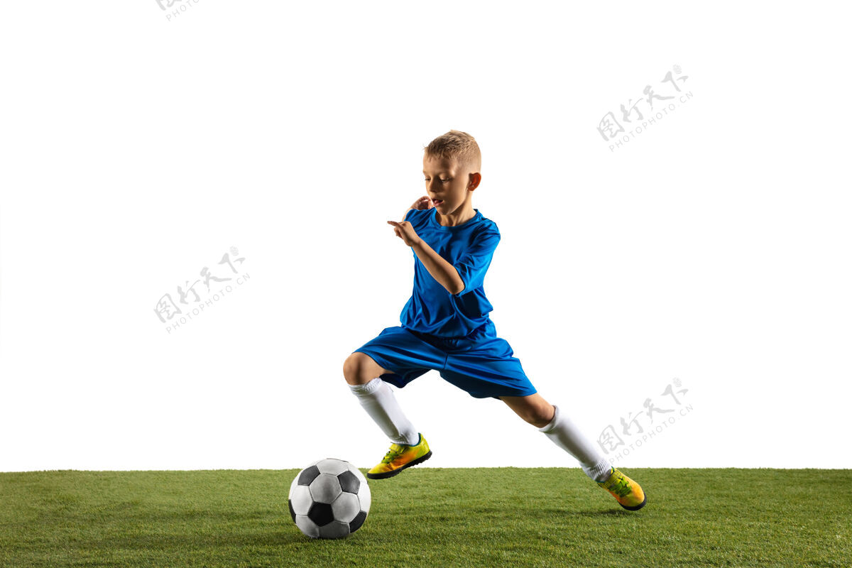 设备穿着运动服的足球运动员或足球运动员的小男孩 为了在白色场地上进球而用球假装或踢目标跑步活跃