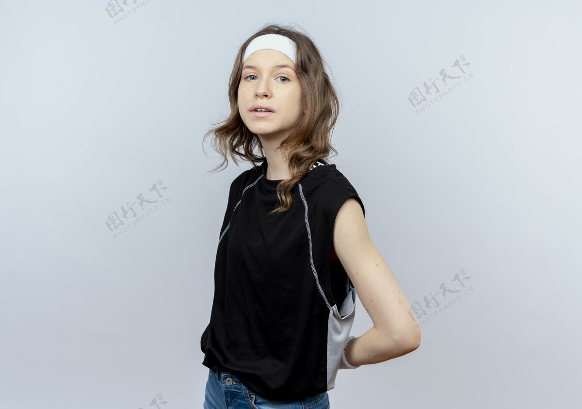 困惑身穿黑色运动服 头戴头巾的年轻健身女孩站在白墙上健康运动装女孩