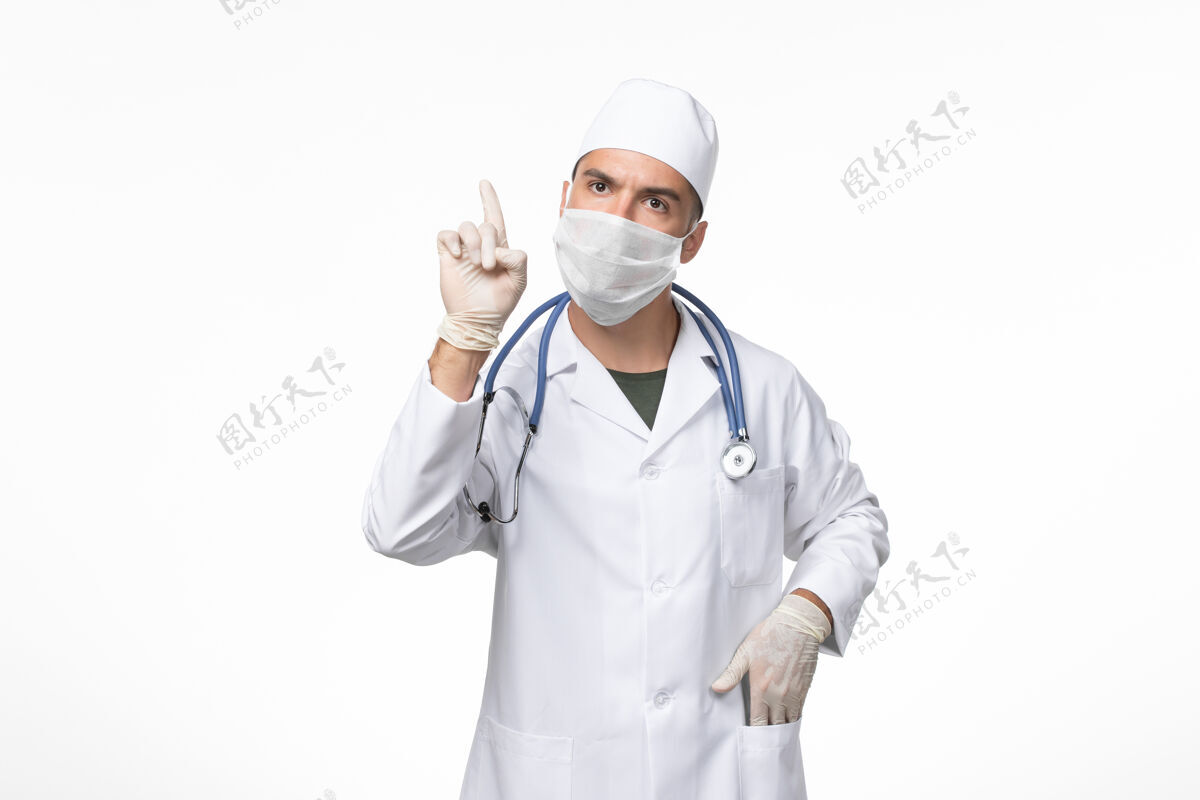 大流行正面图：男医生穿着医疗服 戴着防毒面具 在白色墙壁上抗击柯维德病大流行病毒男性视图男人