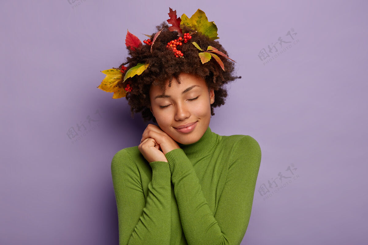 紫色孤零零拍摄的迷人女子斜靠在手上 闭着眼睛 穿着绿色舒适的高领毛衣 头发上插着秋叶和浆果绿色高兴高兴