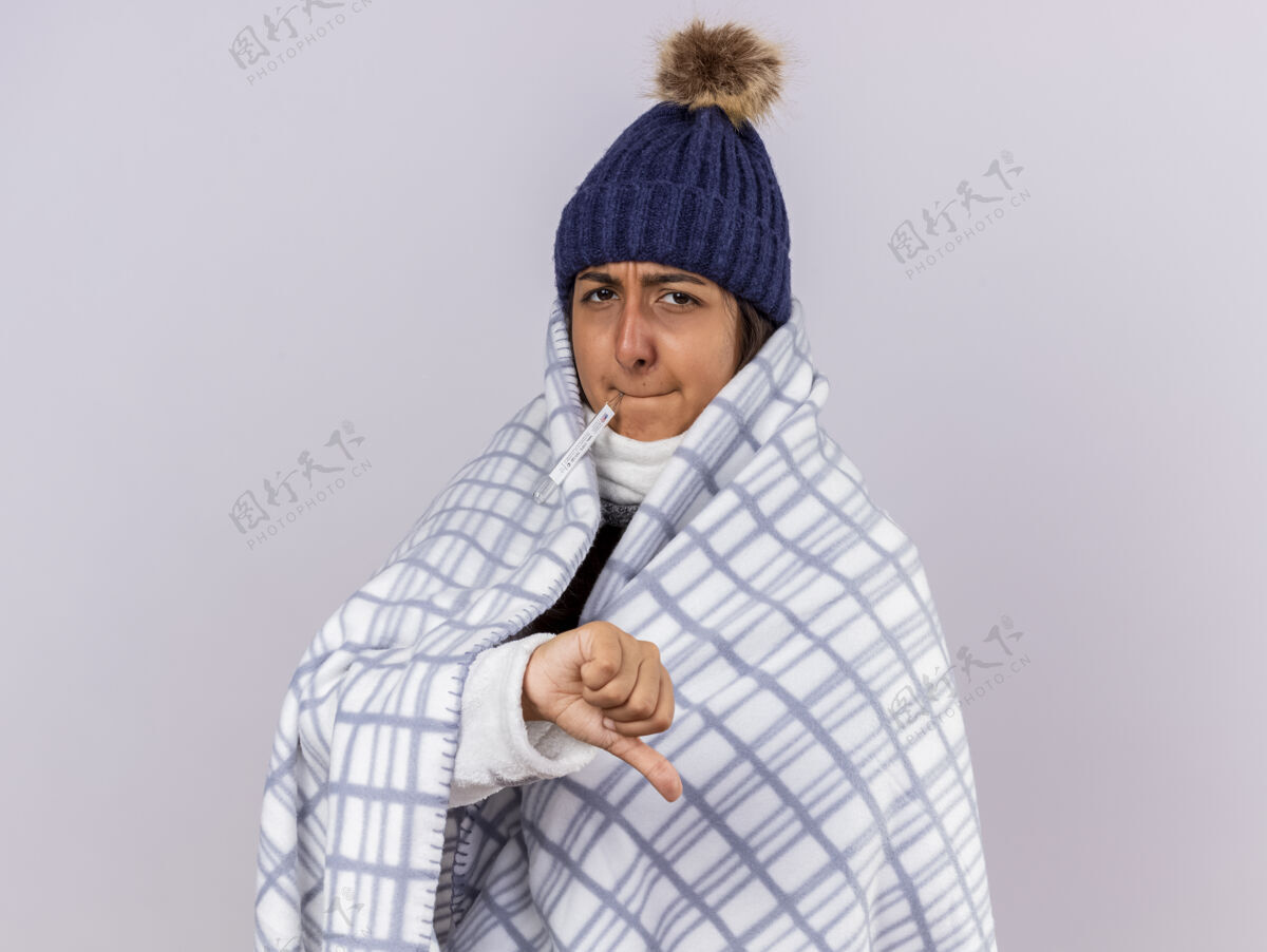 疾病未出嫁的生病的年轻女孩戴着冬天的帽子 用格子布裹着围巾 嘴里放着温度计冬天女孩拇指