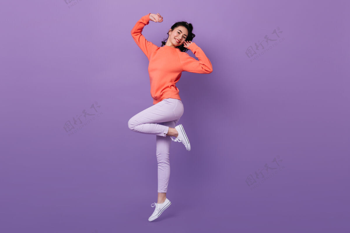 成功可爱的亚洲女人单腿站立在紫色背景上跳跃的迷人时尚日本女人的全貌减肥女士有趣