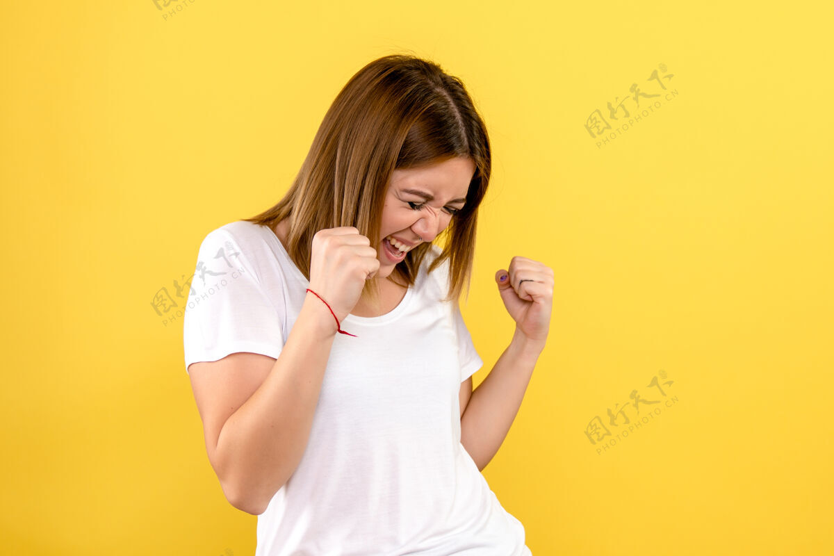 女士年轻女子在黄墙上欢庆的正面图模特快乐情感