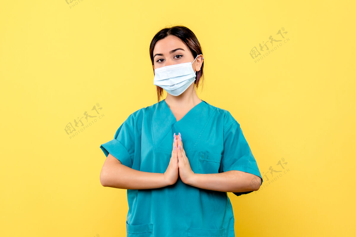 漂亮戴着面具的医生的侧视图在为患有冠状病毒的病人祈祷肖像看专业