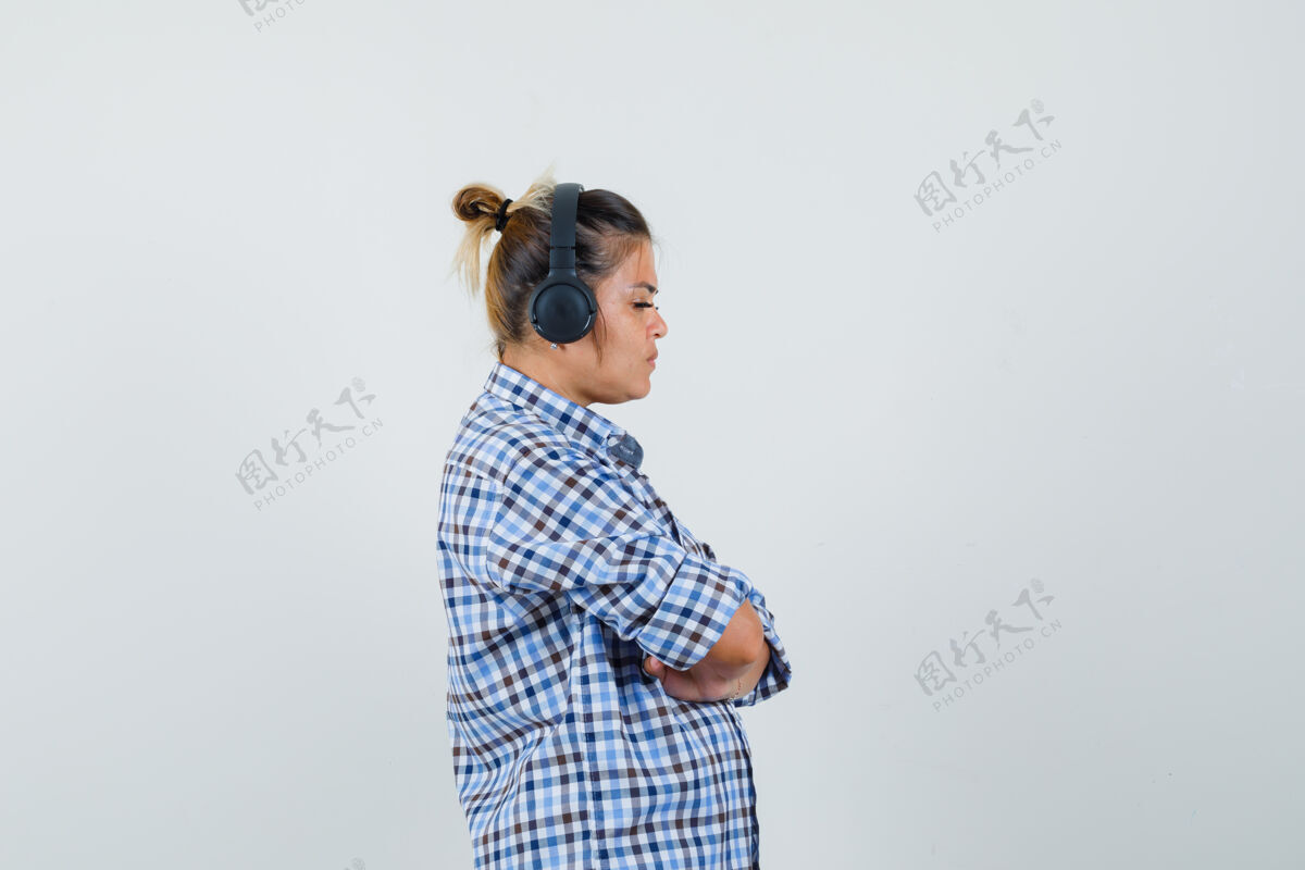 专注穿着格子衬衫 戴着耳机听音乐 看起来很专注的年轻女子女人聆听成人