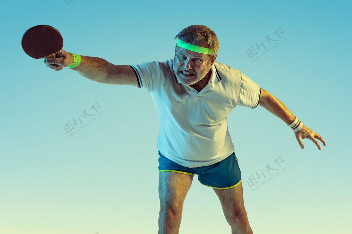 球员资深男子在霓虹灯下在梯度背景下打乒乓球身材魁梧的白种人男模保持活跃 运动一教练健康