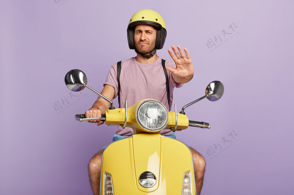 司机不满的家伙戴着头盔开着黄色的摩托车男人保护手掌