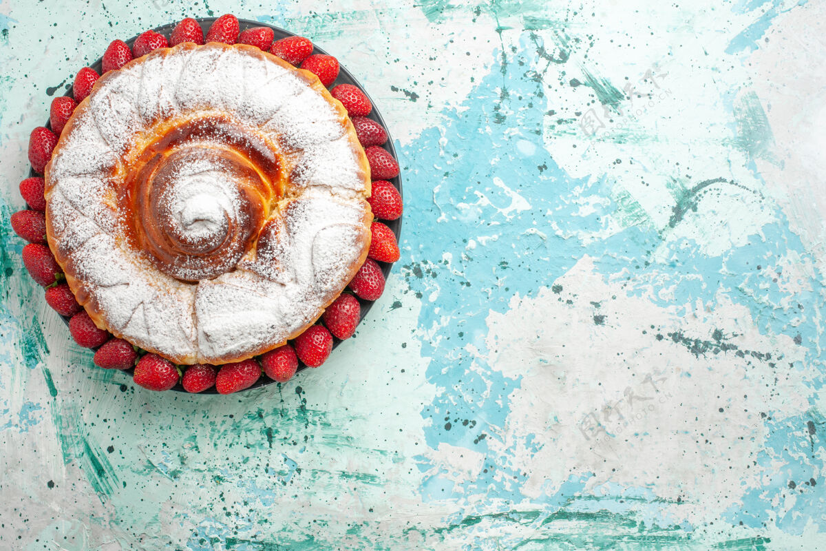 派顶视图糖粉蛋糕与新鲜的红色草莓淡蓝色的表面顶部线圈饼干