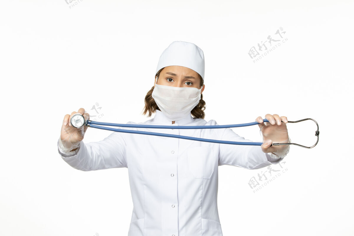 浅白色正面图年轻女医生带着无菌口罩因冠状病毒在浅白色表面流行病男高尔夫