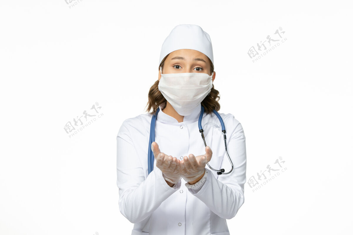 医生白色办公桌上戴着无菌口罩和手套的年轻女医生正面大流行冠状病毒