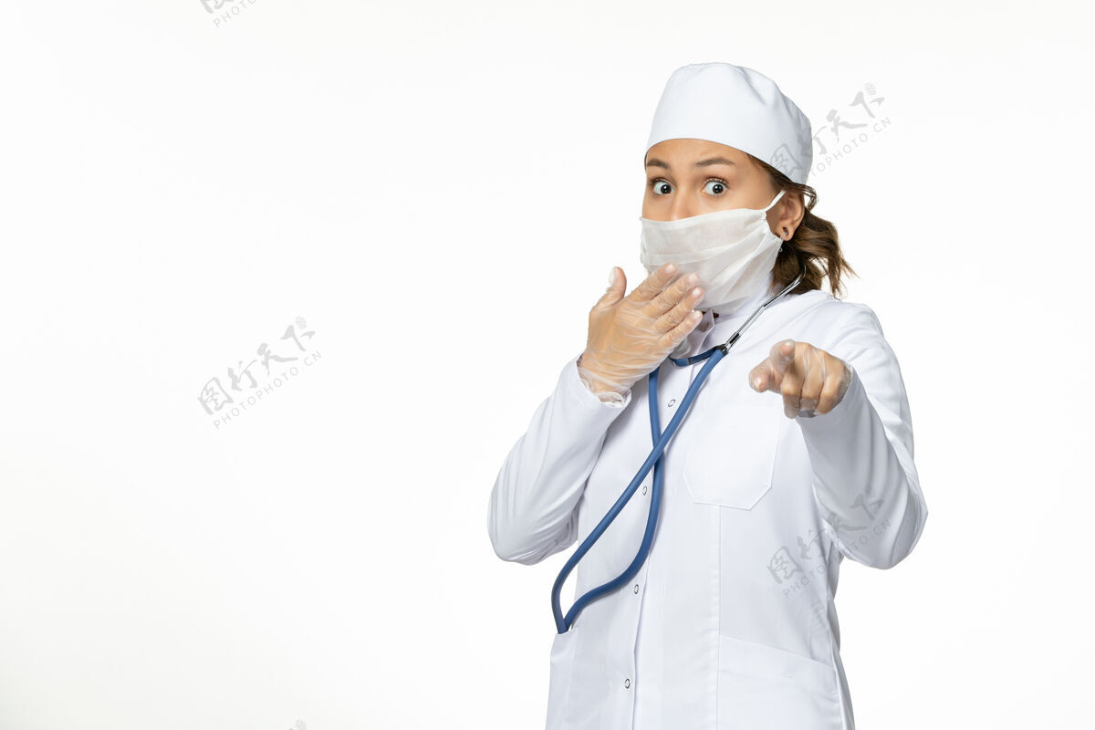 女性正面图年轻女医生戴着无菌防护口罩因白色书桌上有冠状病毒听诊器冠状病毒穿戴