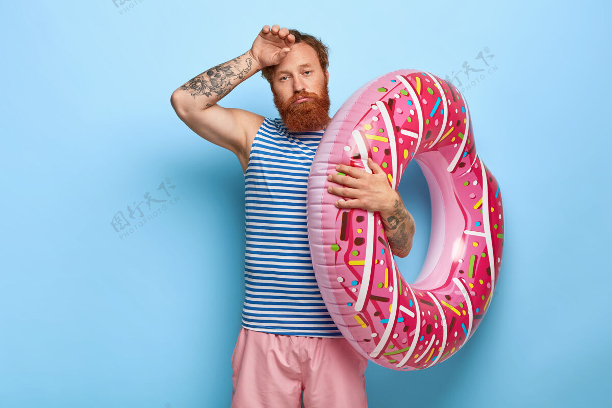 姿势疲惫的红发男子与甜甜圈池浮子合影的镜头活动累站