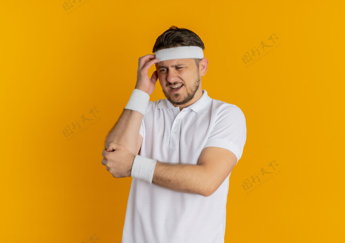 健身身穿白衬衫 头箍的年轻健身男子站在橙色背景下 茫然地看着一旁衬衫男人靠边