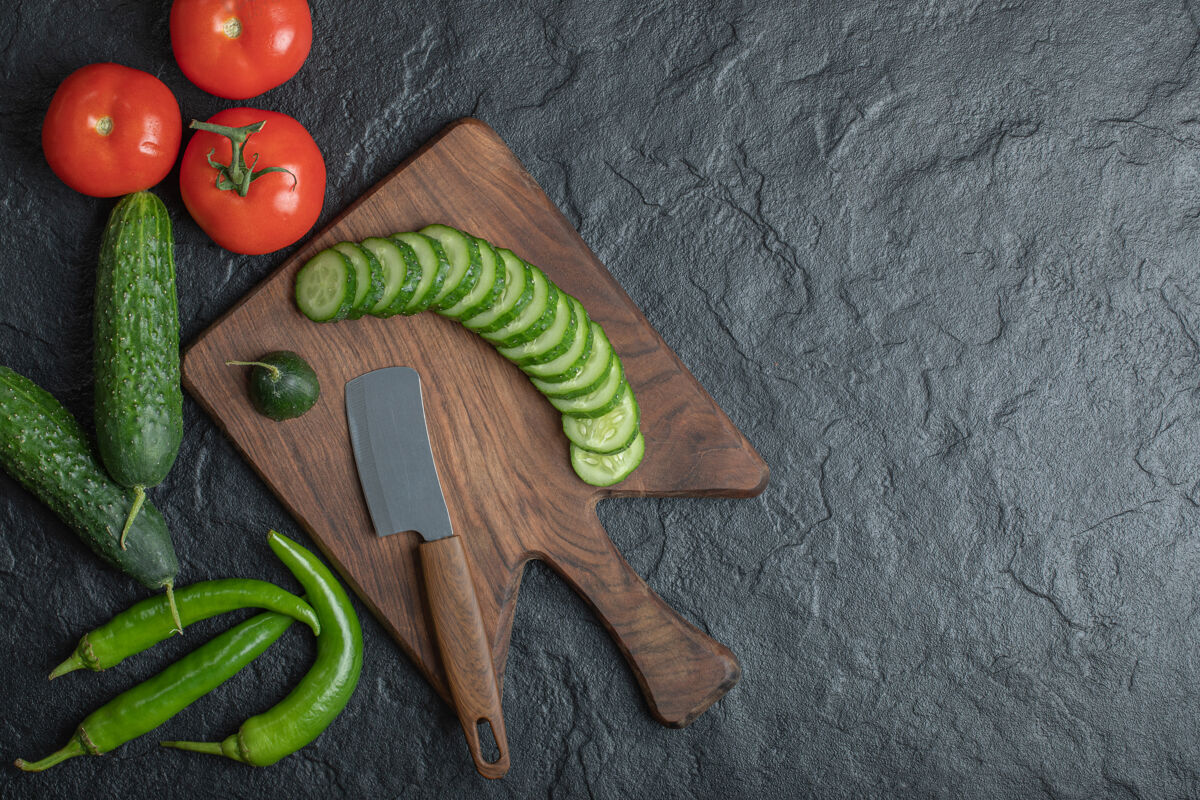 生的木板上的新鲜蔬菜西红柿黄瓜和青椒高品质照片生的刀一串