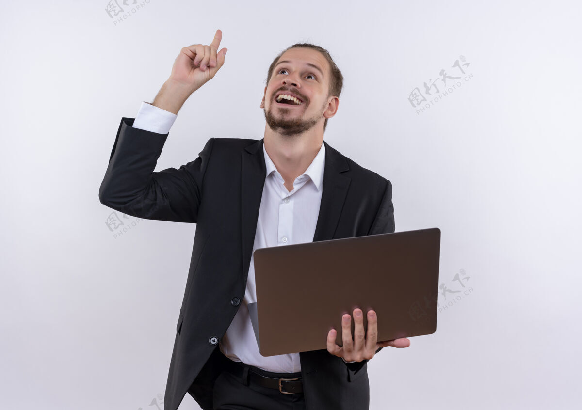 男士穿着西装的帅哥手拿笔记本电脑 手指朝上 站在白色的背景上欢快地笑着拿着商务手指