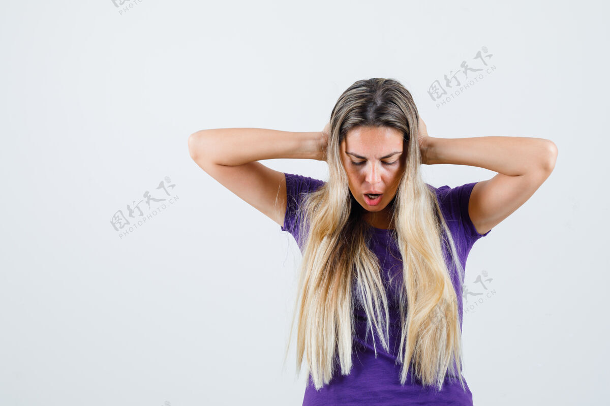 可爱身穿紫罗兰色t恤的年轻女性 手放在头上 看上去精疲力尽 正面视图手时尚美丽