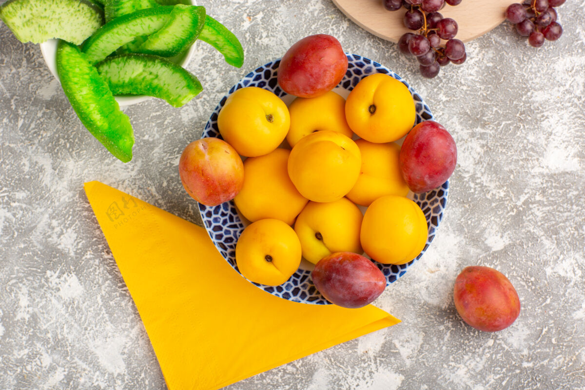里面顶视图新鲜甜杏黄色水果盘内与李子和葡萄在白色办公桌上醇香维生素桌子