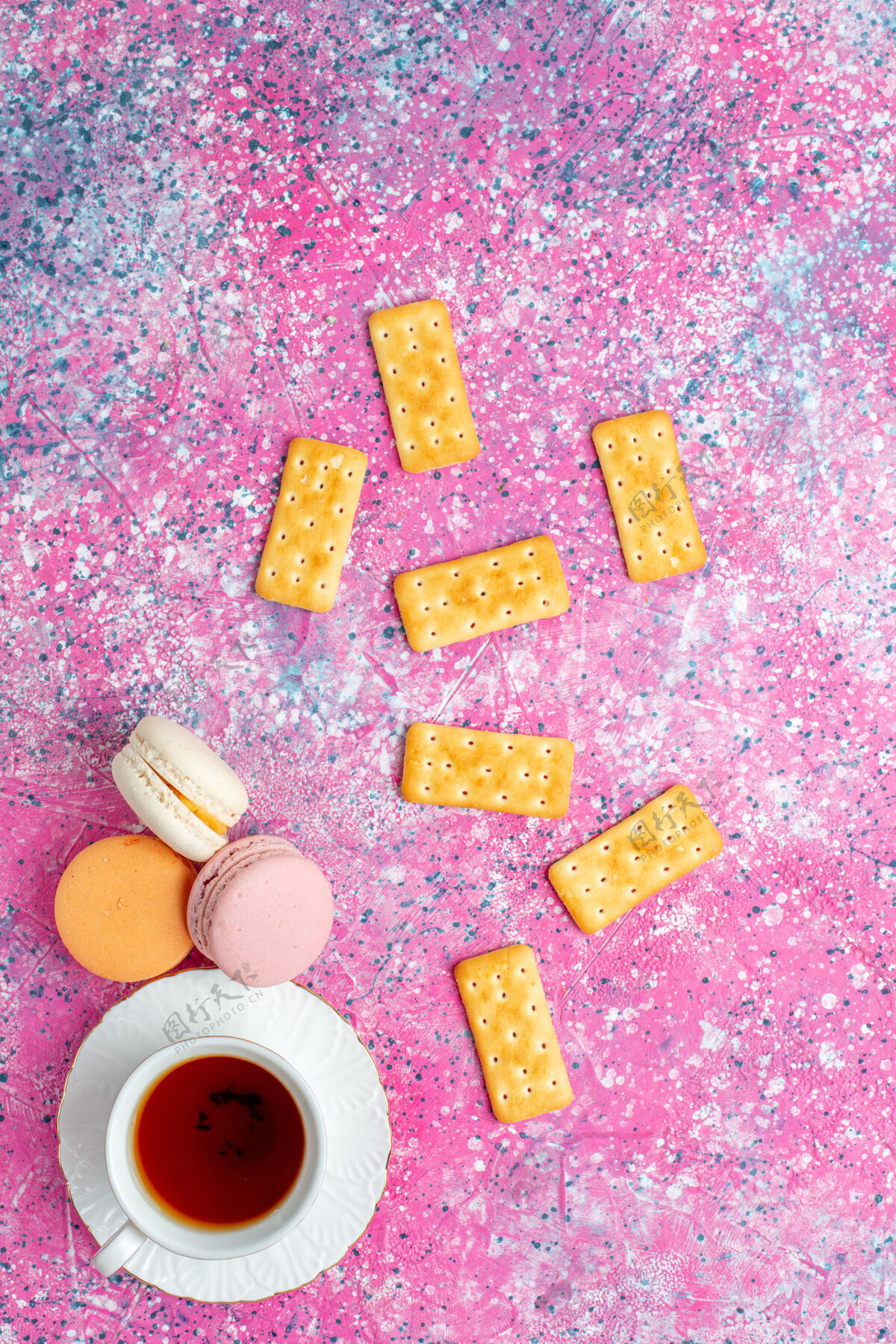 饼干在粉红色的桌子上可以俯瞰一杯茶 里面有法国马卡龙和饼干茶法国顶部