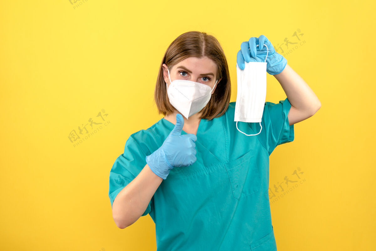黄色黄色空间上戴着蓝色手套和面罩的女医生的前视图正面视图专业