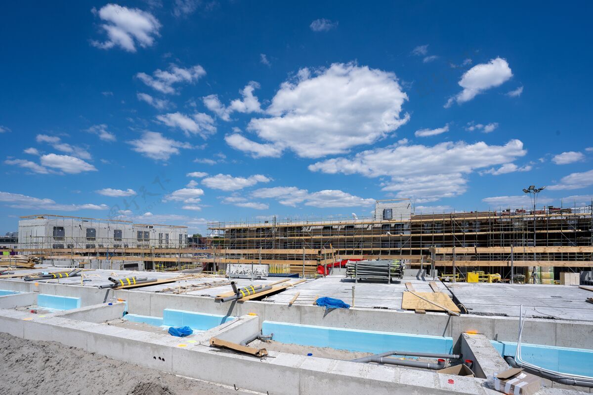 混凝土一个建筑工地的水平镜头 在湛蓝的天空下搭脚手架维护施工建筑