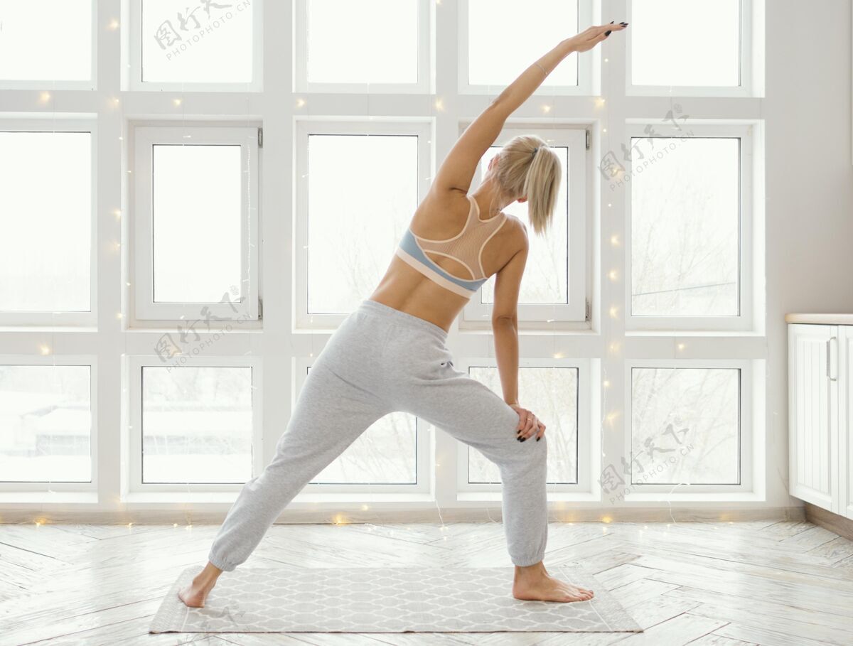 瑜伽垫后视图：坐在垫子上锻炼的女人运动室内房子