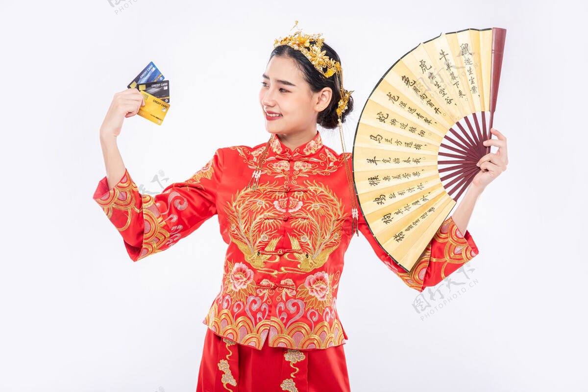 旗袍女人穿旗袍西服拿着中国人的手扇子秀信用卡可以用来过年购物中国新年信用卡中国民族