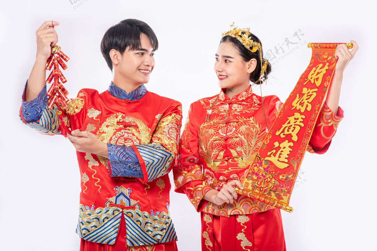 男孩穿旗袍套装的男女一起用中国贺卡和鞭炮庆祝中国新年传统节日旗袍鞭炮