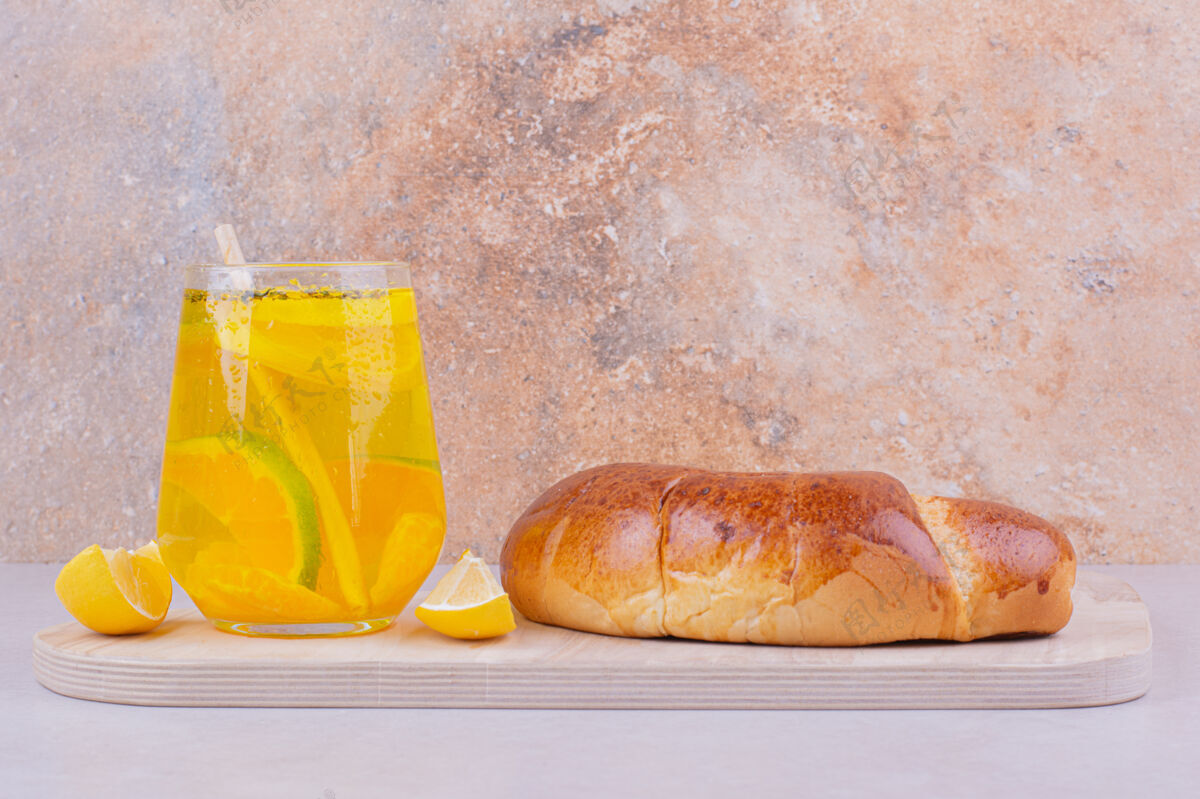 柑橘羊角面包和一杯柠檬水在白色的表面新鲜的香料水