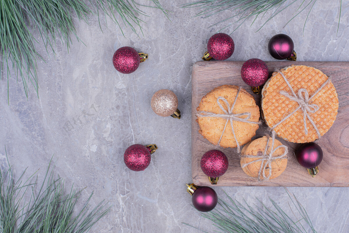 饼干放在木板上的饼干 周围放着闪闪发光的红色圣诞球精致饼干美味