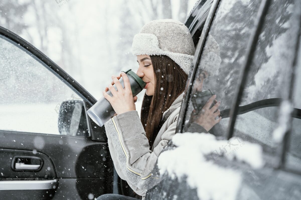 旅行女人的侧视图在旅途中喝一杯热饮 享受雪景公路旅行探索自然