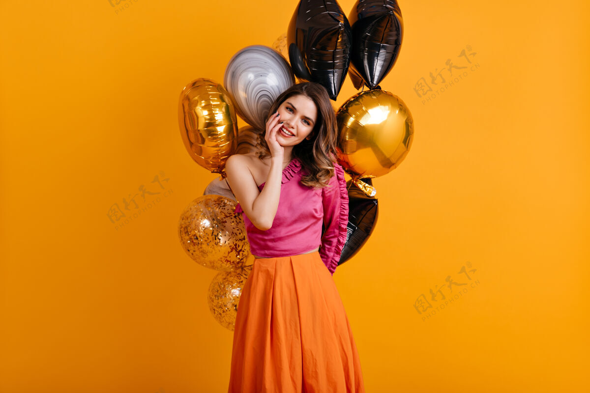 欢笑在橘色墙上摆造型的神奇生日女人派对成人生日