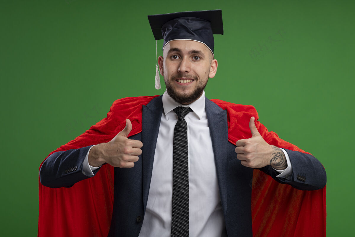 拇指身穿红色斗篷 满脸幸福 大拇指竖立在绿色墙壁上的毕业男子毕业典礼表演表情