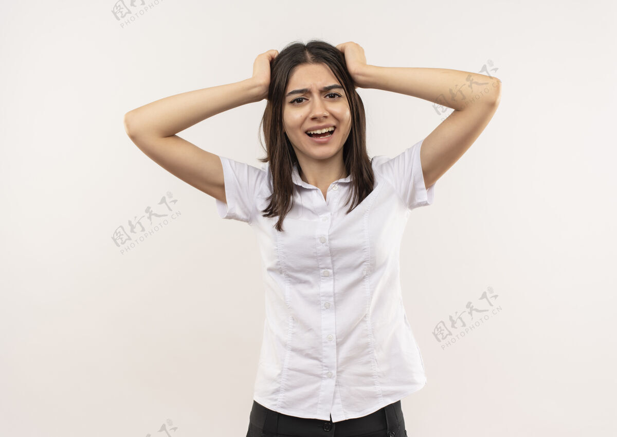 衬衫穿白衬衫的年轻女孩站在白墙上拉头发发疯站野性姿势