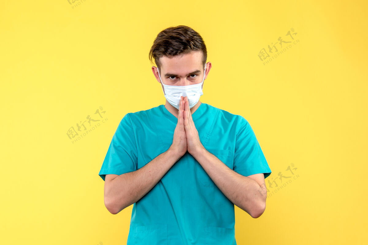 表演男医生在黄墙上祈祷的正面图喜剧演员医学男人